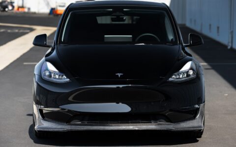 Front shot of a Tesla Model Y featuring Unplugged Performance's aerodynamic carbon fiber front lip spoiler and UP-05 wheels, designed for a sportier, more aggressive appearance