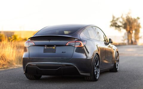 Tesla Model Y with Unplugged Performance UP-05 forged wheels, red big brake kit, front carbon fiber lip spoiler, rear diffuser, and high-efficiency rear spoiler, showcasing a sleek performance stance.