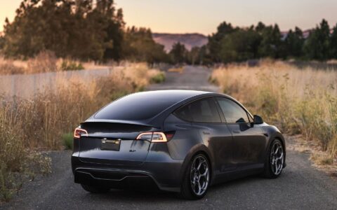 Tesla Model Y with Unplugged Performance UP-05 forged wheels, red big brake kit, front carbon fiber lip spoiler, rear diffuser, and high-efficiency rear spoiler, showcasing a sleek performance stance.