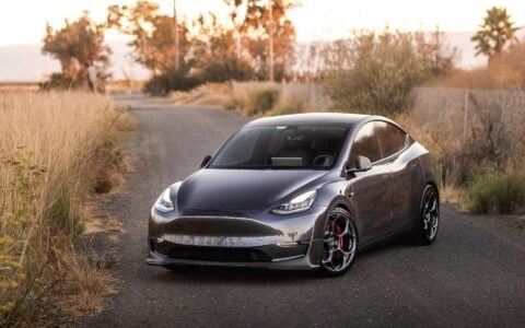 3/4 pose of Tesla Model Y with Unplugged Performance UP-05 wheels, front carbon fiber lip spoiler, and performance coilovers for a lowered, aggressive stance.